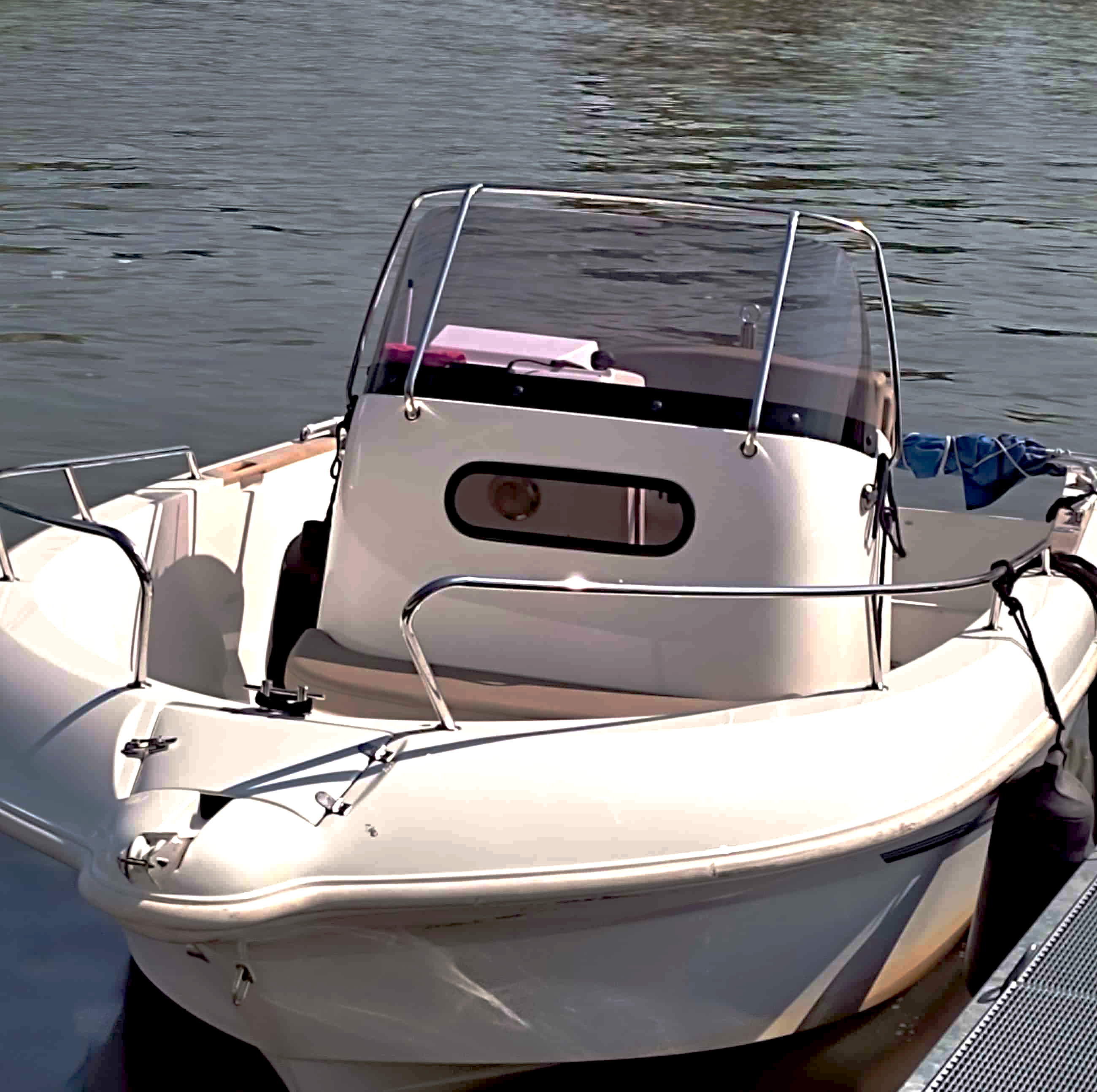 Ein an einem Steg liegendes beigenes Motorboot mit Platz für circa 4 Personen.