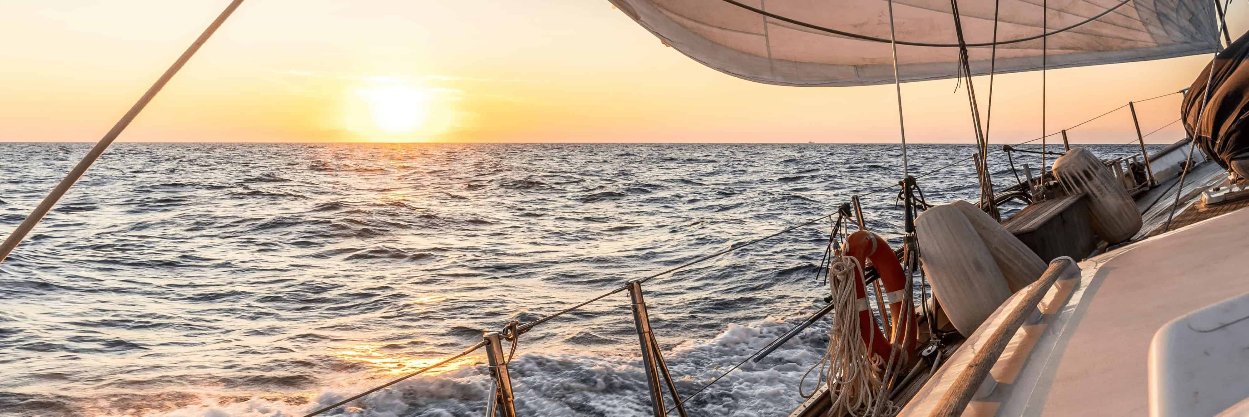 Das Deck eines Segelboots auf offenem Meer bei Sonnenuntergang.
